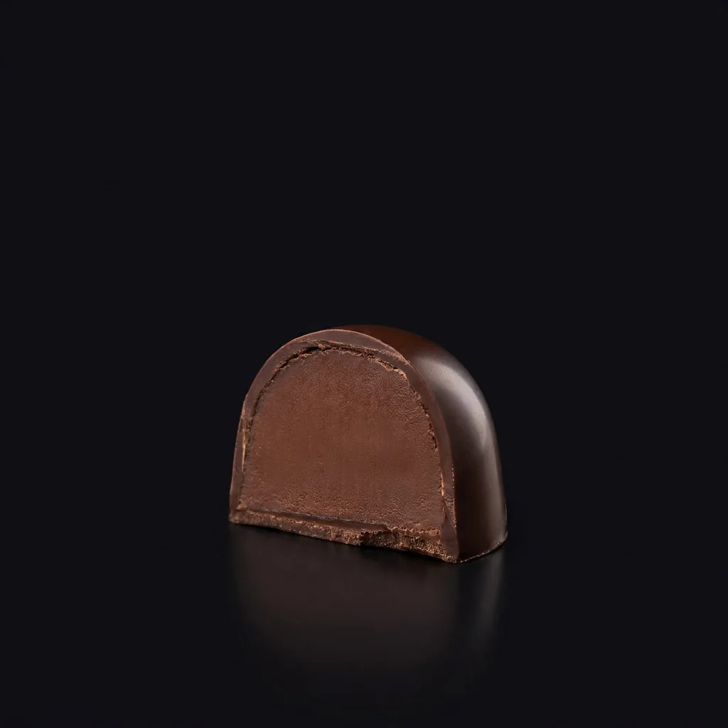 Bombón de Ganache de maracuyá y chocolate negro, cortado para mostrar el relleno